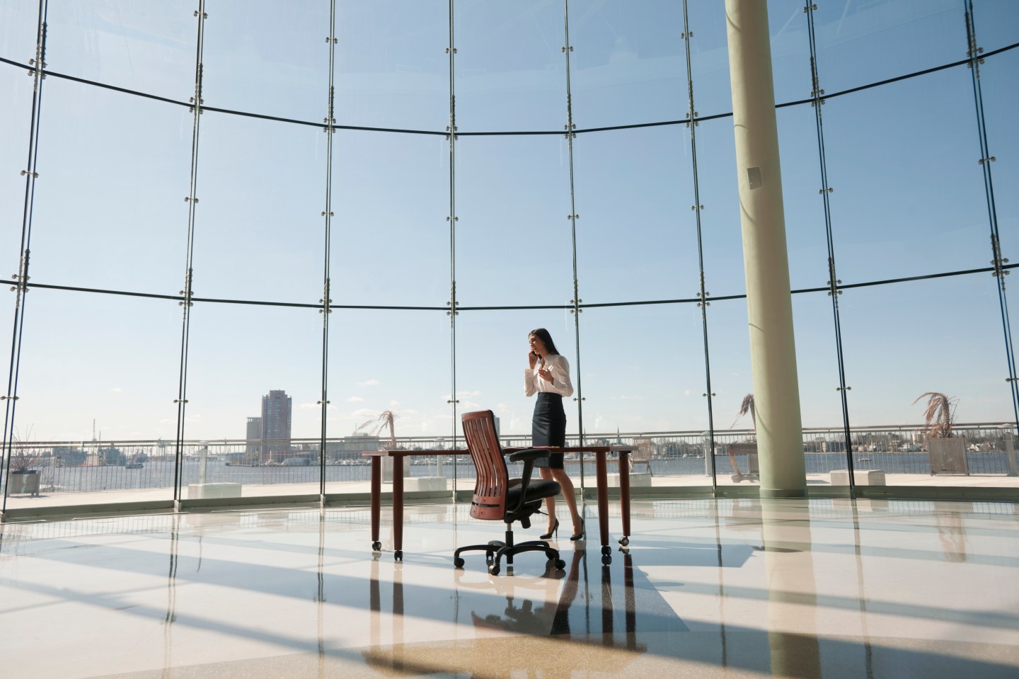 Businesswoman working in large office with glass wall