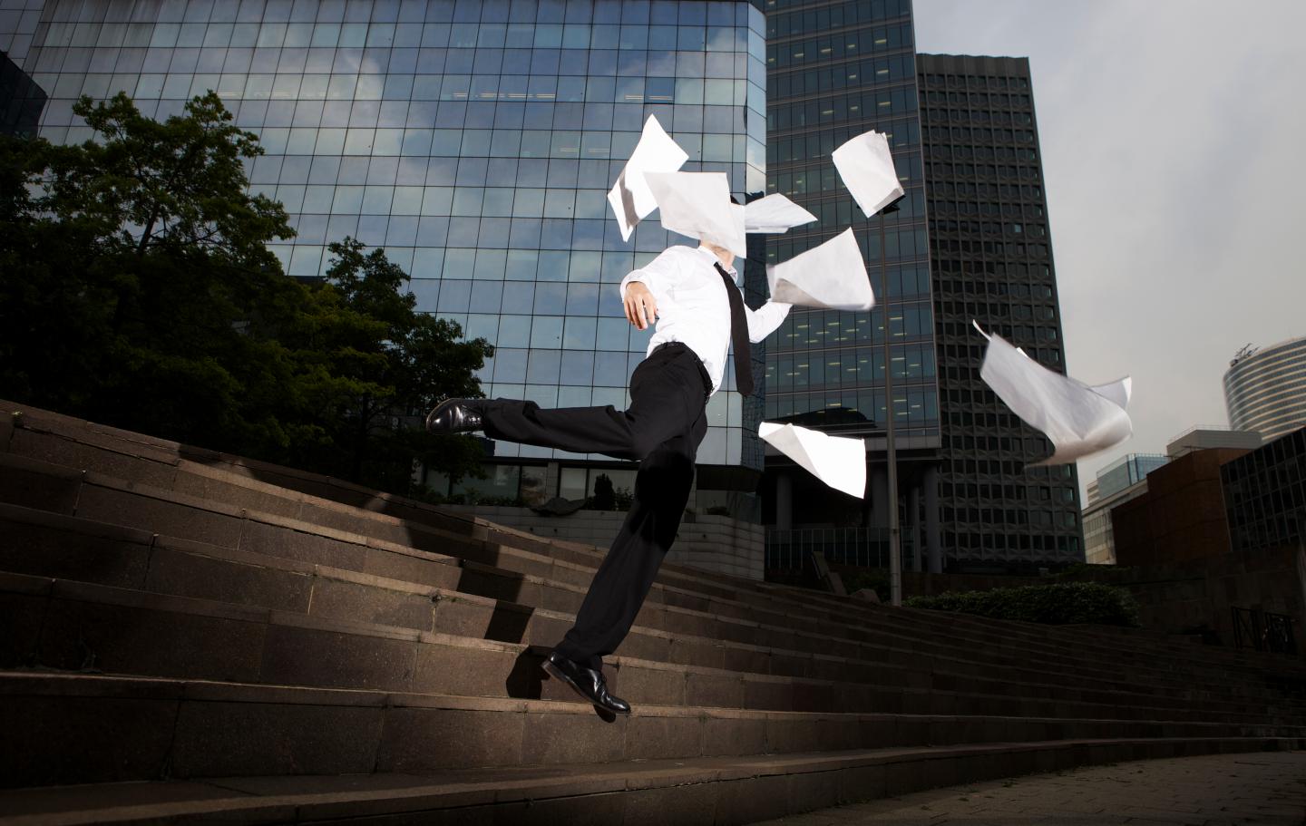 Businessman falling down steps with flying paper