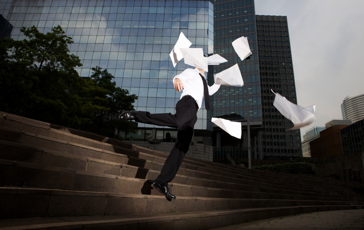 Businessman falling down steps with flying paper