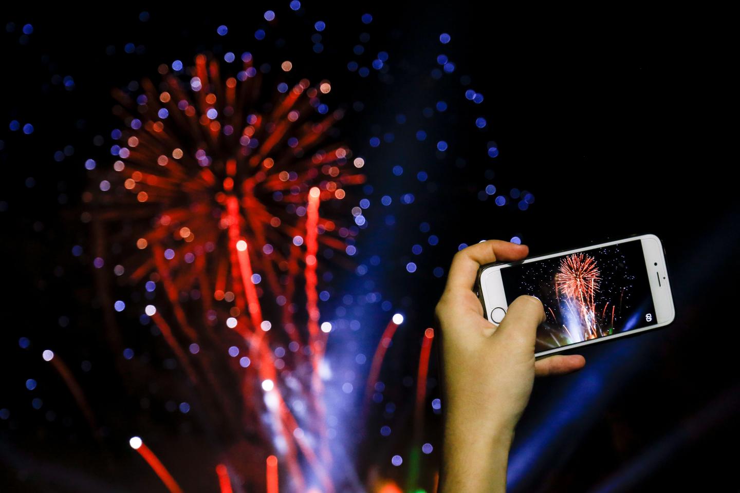 woman takes a picture with her smartphone of fireworks