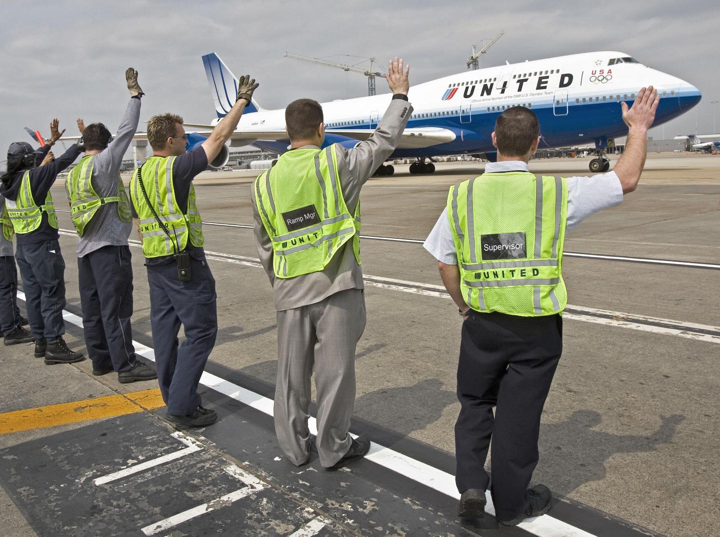 Ground crew members wave goodbye to Unit