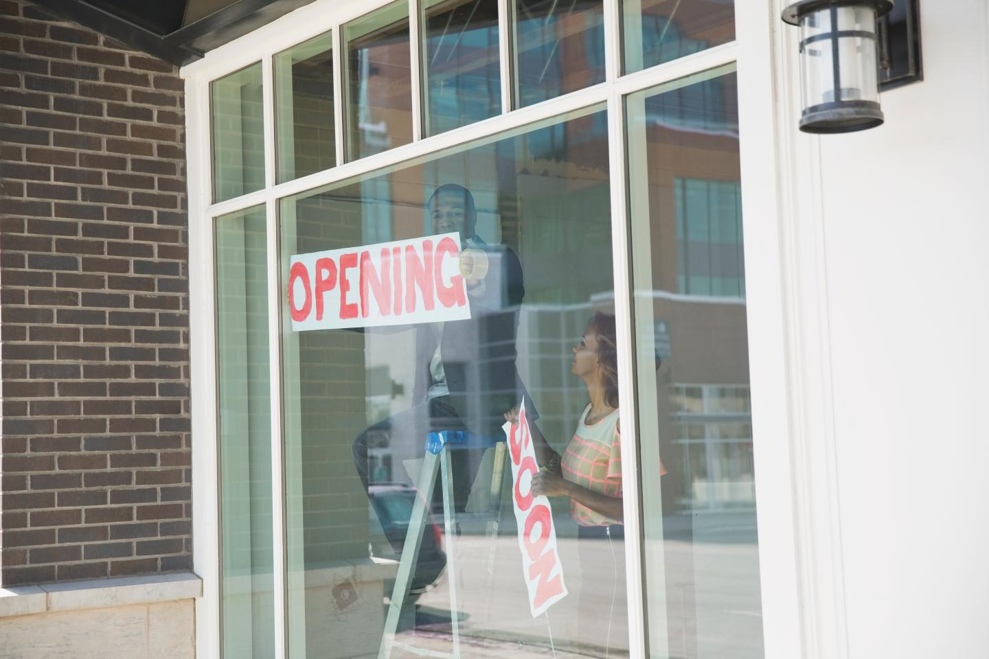 Business owners hanging Opening sign in shop window