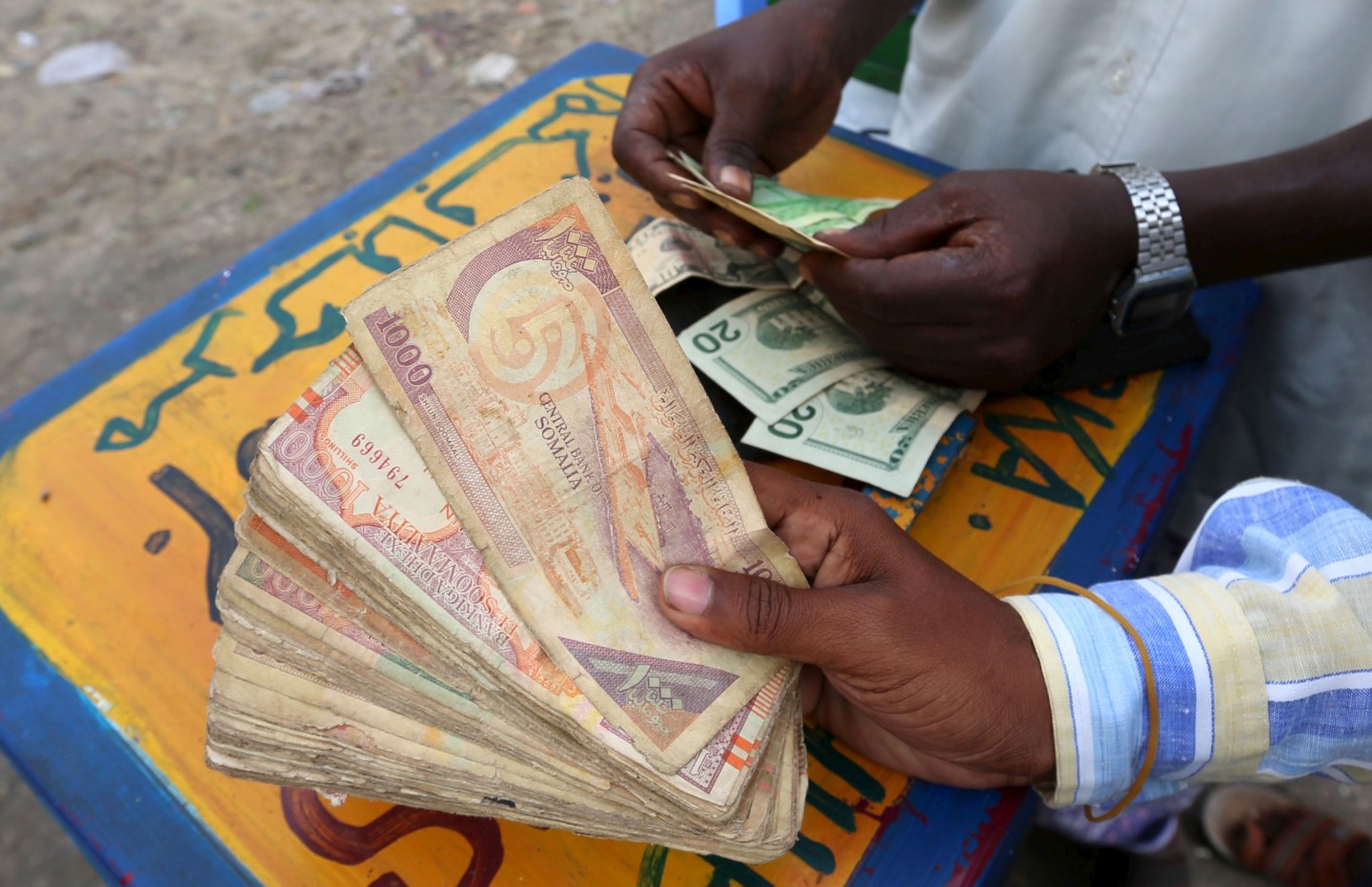 FILE PHOTO: Somalian shillings and U.S. dollars are held at an open forex bureau in Somalia's capital Mogadishu