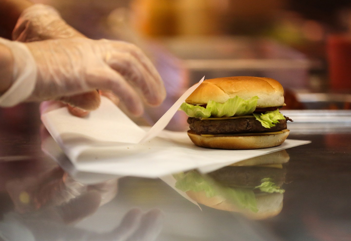 An employee prepares to wrap a freshly made hamburger.