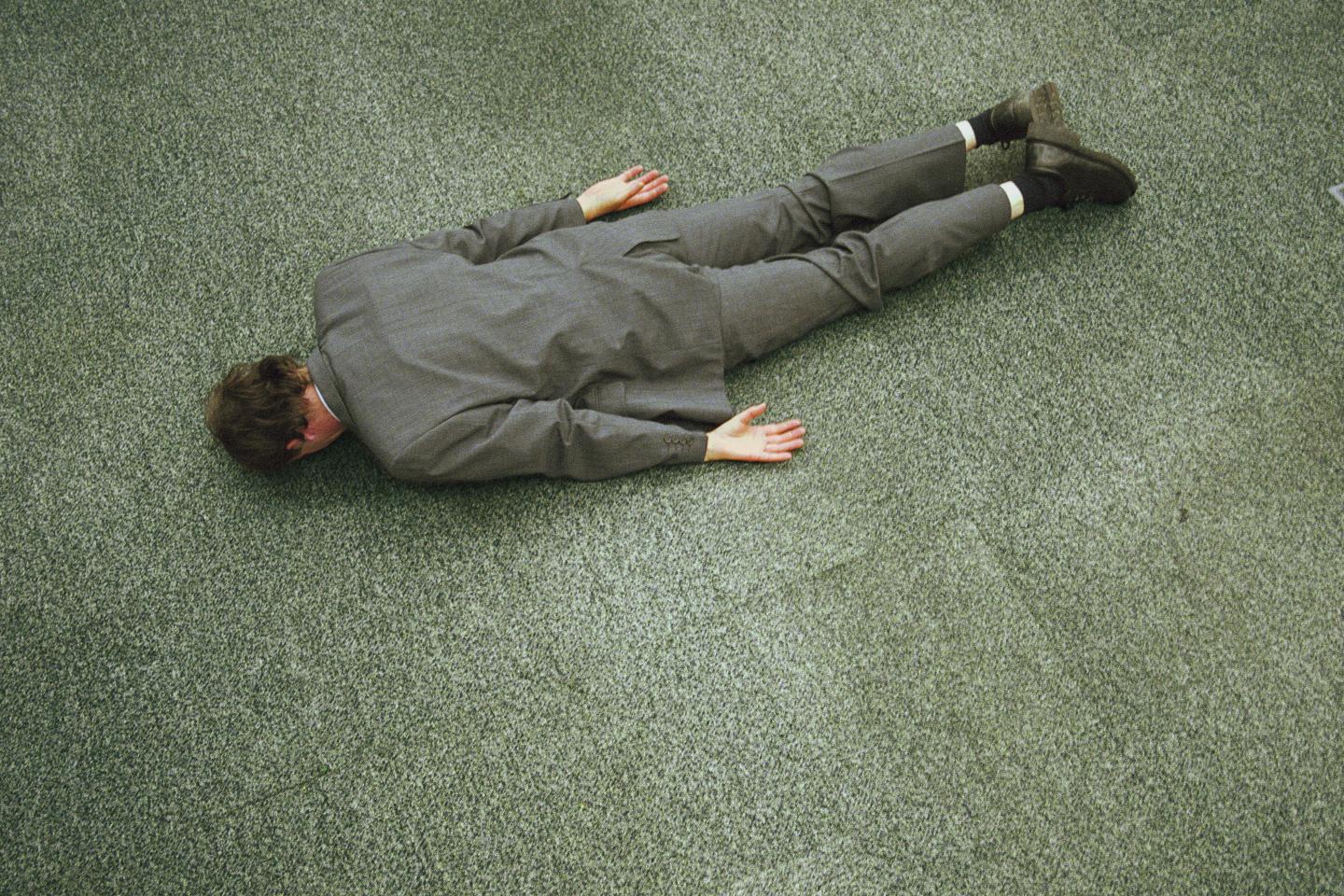 Businessman lying face down on floor, elevated view