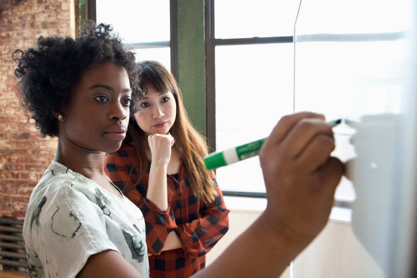 Businesswoman writing on whiteboard in meeting