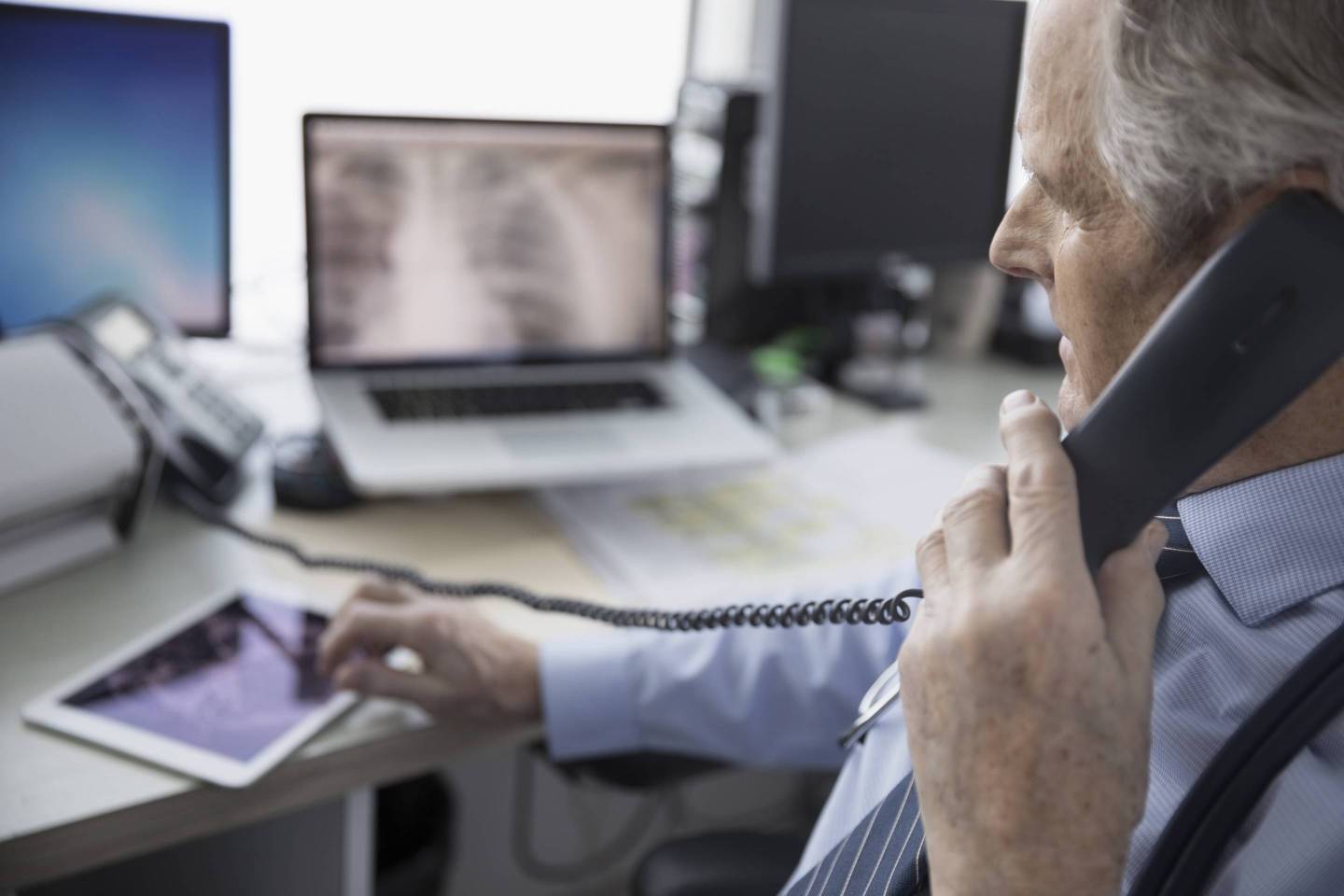 Male doctor talking on telephone and using digital tablet in clinic doctor