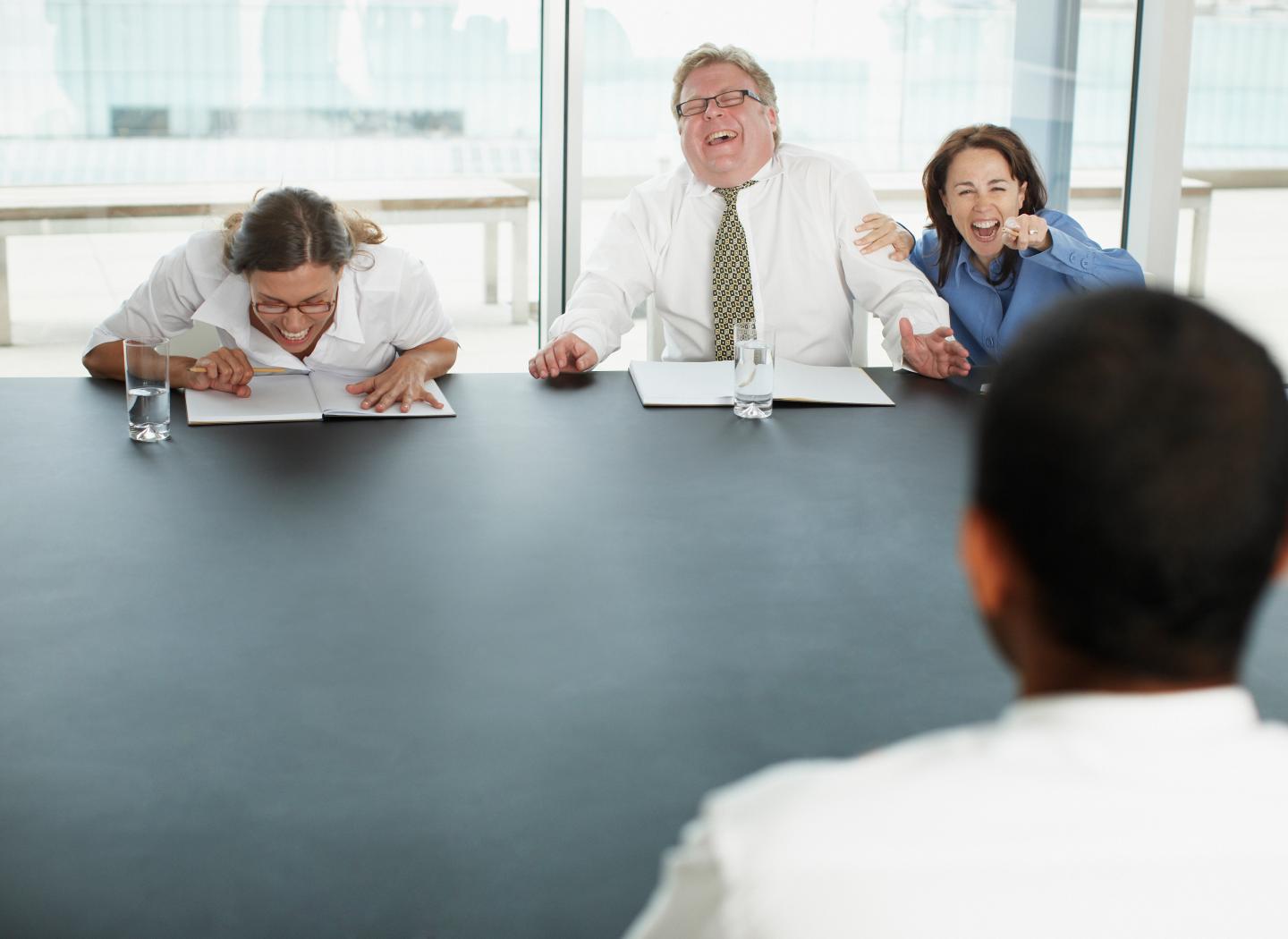 Businesspeople laughing at applicant in interview