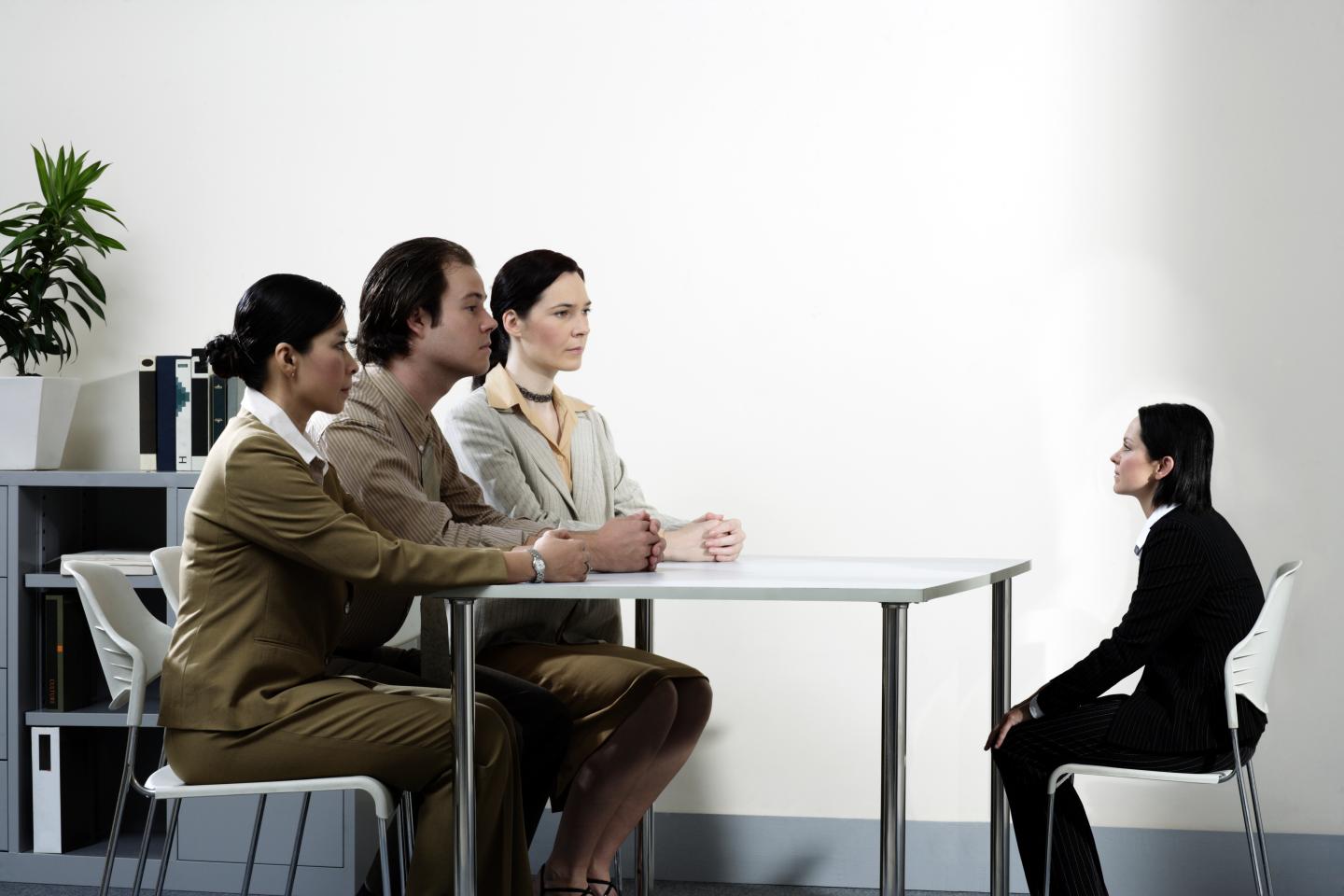 Three giant business people interviewing small female colleague (Digital Composite)