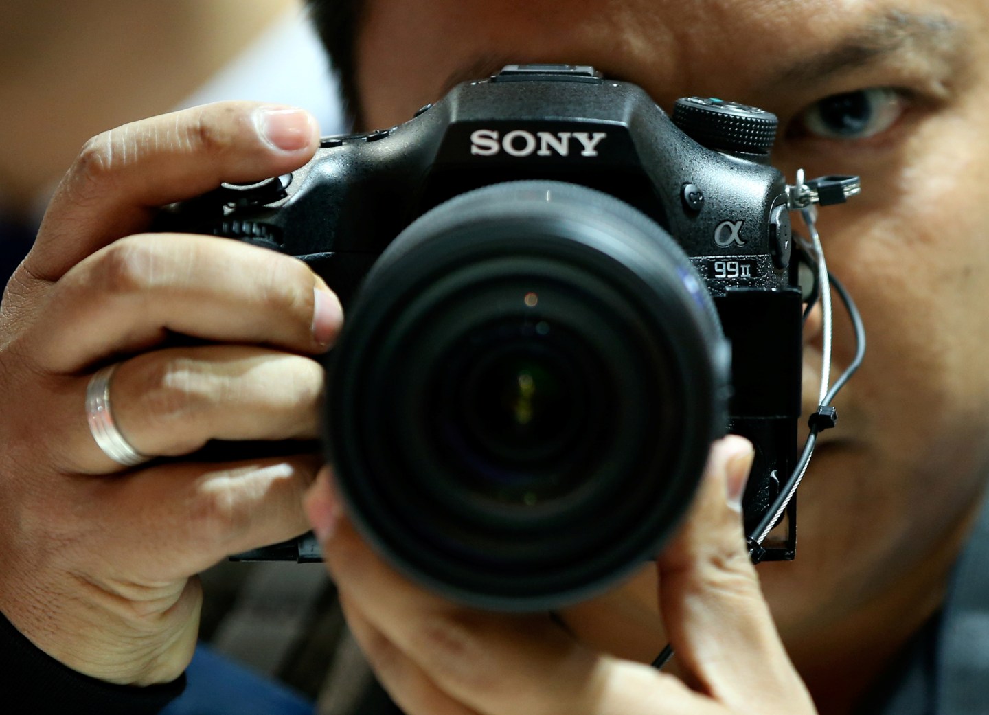 A visitor checks out the new Sony Alpha 99 Mark II DSLR camera at the Sony booth on the Photokina fair for imaging in Cologne