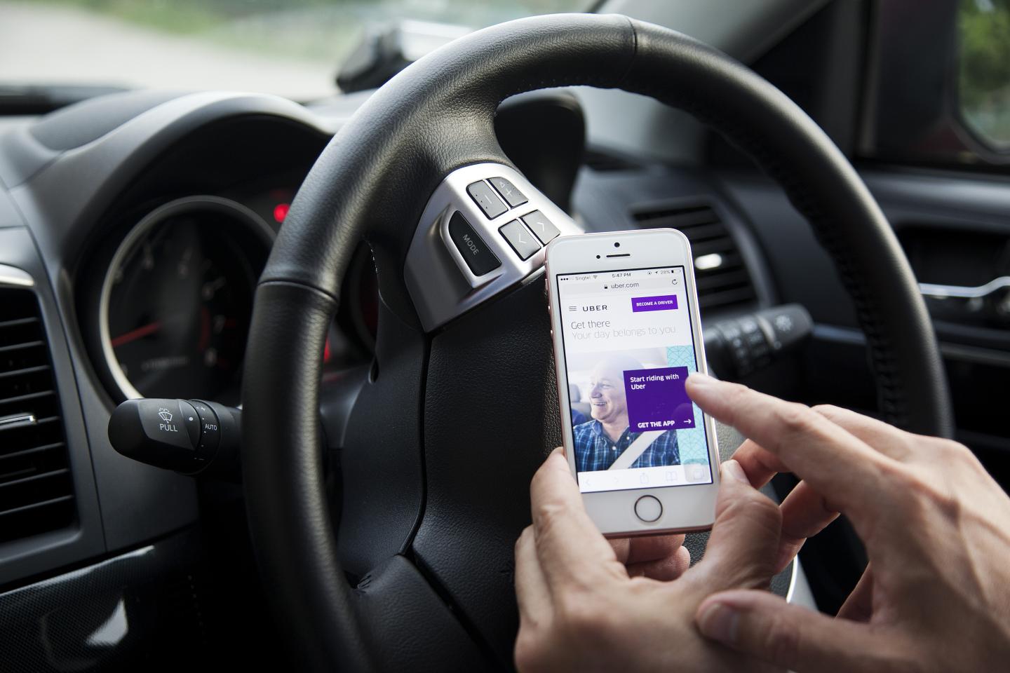 A driver for the Uber Technologies Inc. ride-hailing service uses the company's app on a smartphone in an arranged photograph in Singapore, on Monday, Oct. 31, 2016.