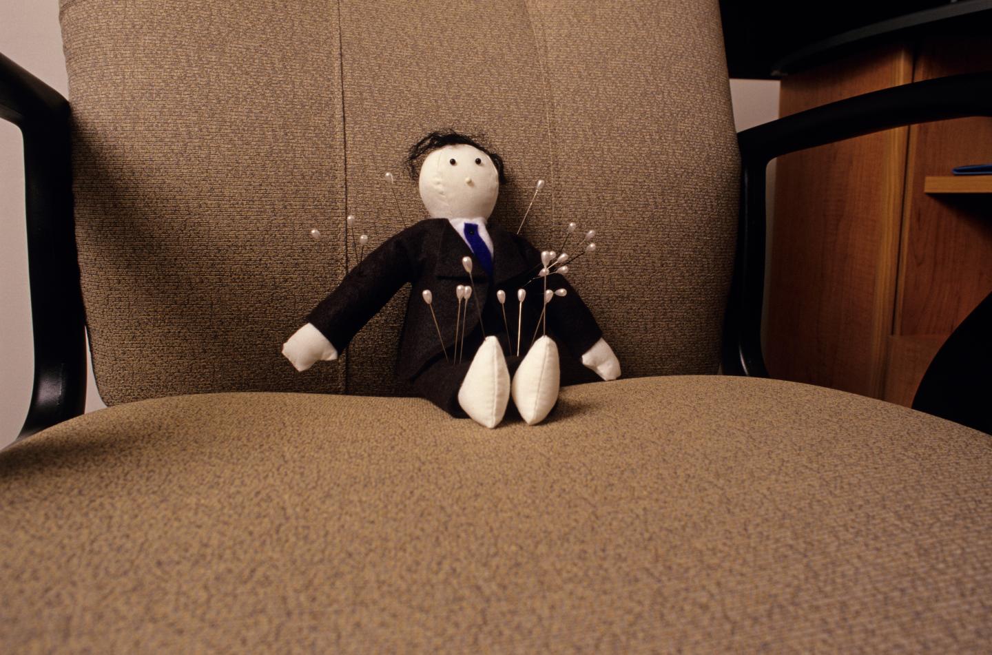 Voodoo doll sitting in chair in office
