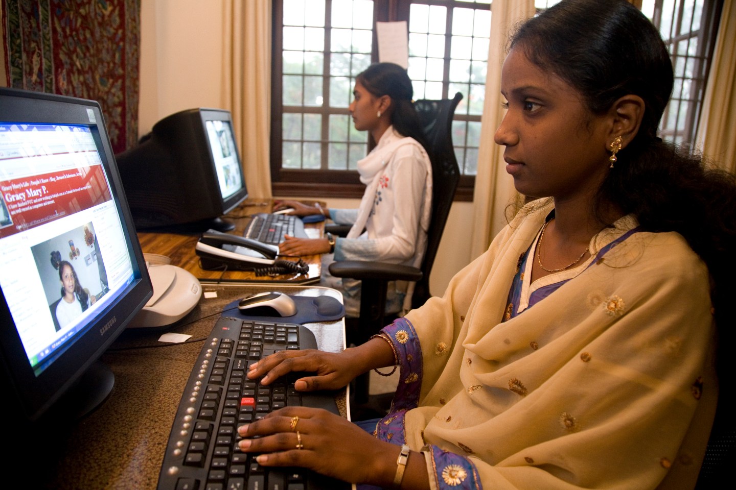 An employee in Bangalore works on her computer in a small office