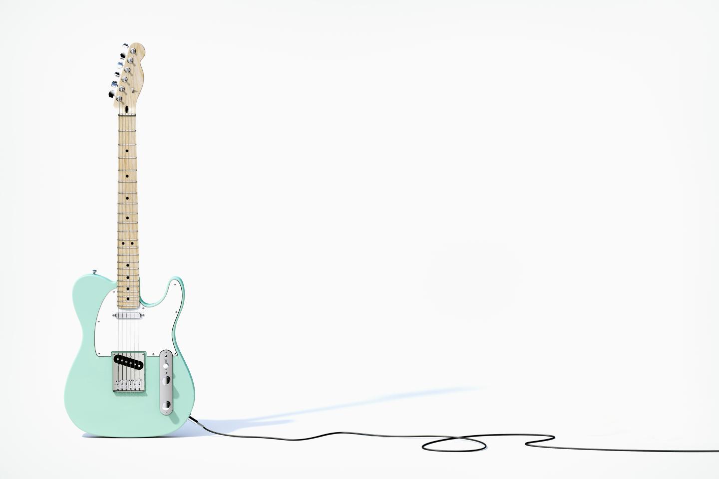 Green guitar balancing on white background
