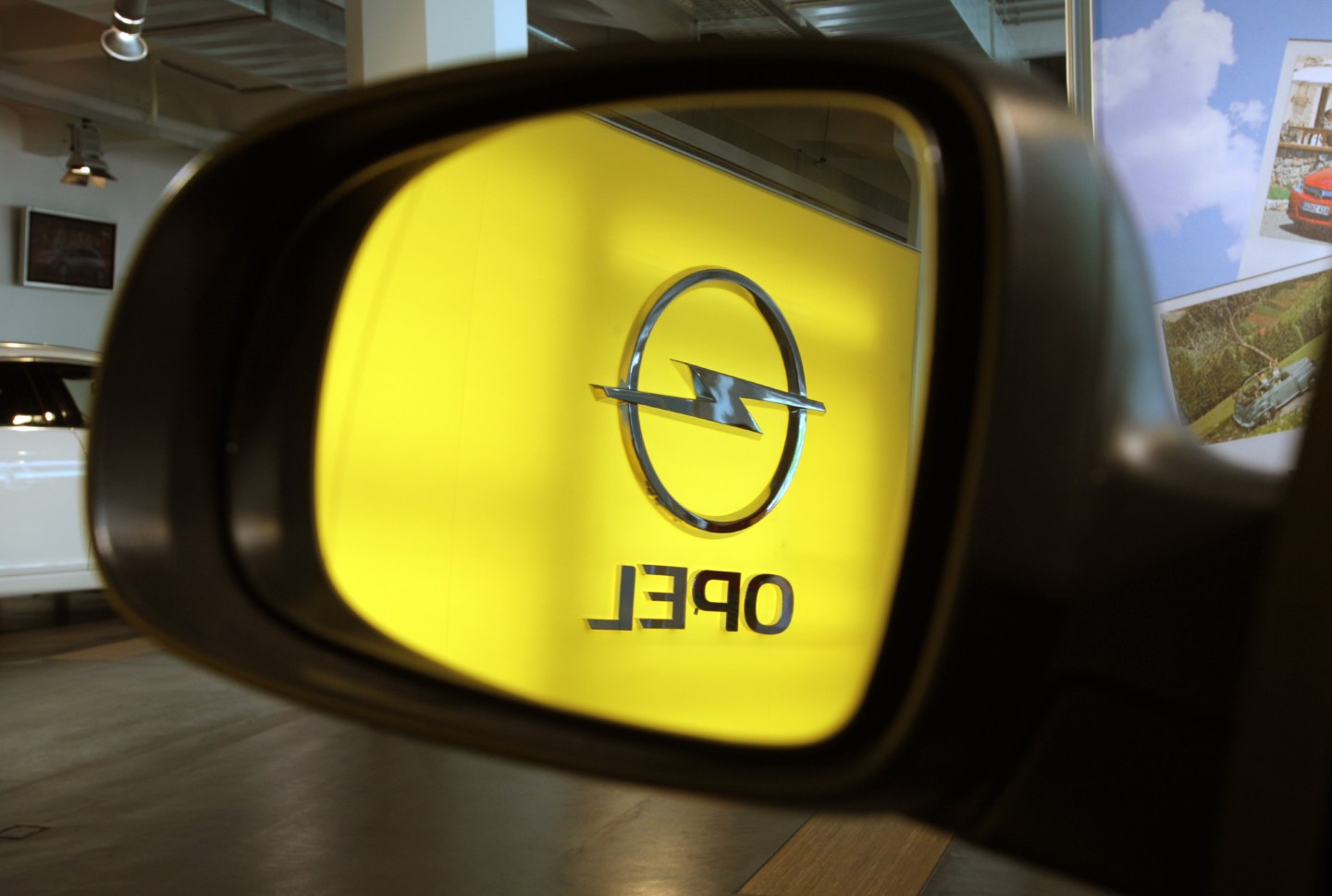 The Opel logo is reflected in a rear-view mirror at an Opel dealership Germany.