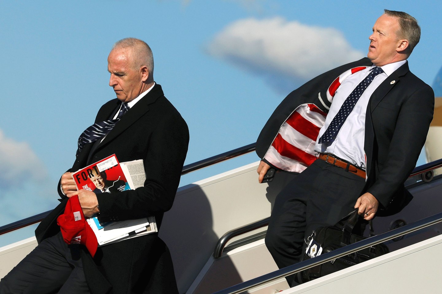 Schiller carries a red USA hat and a copy of Fortune magazine with Trump on the cover as he and Spicer deplane from Air Force One at Joint Base Andrews