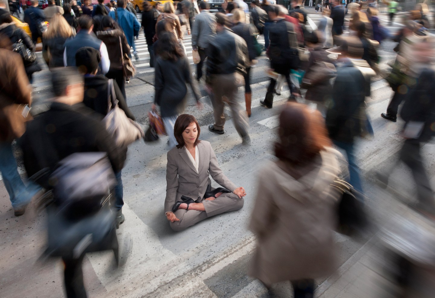 Businesswoman practicing yoga in busy urban crosswalk