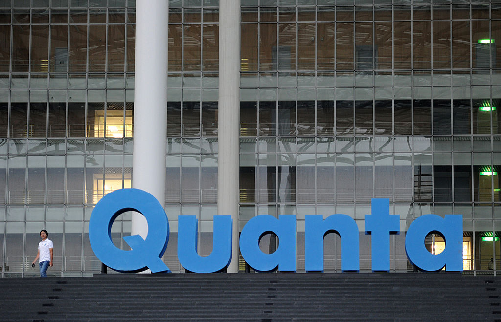 A man walks past a Quanta logo outside t