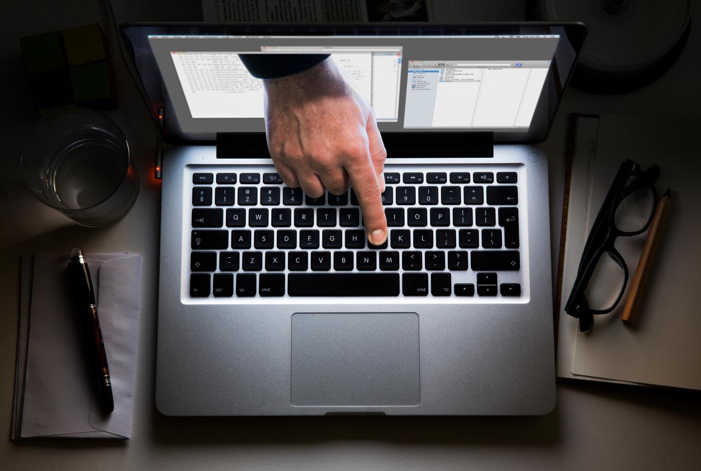 Hand appearing from laptop screen touches keyboard