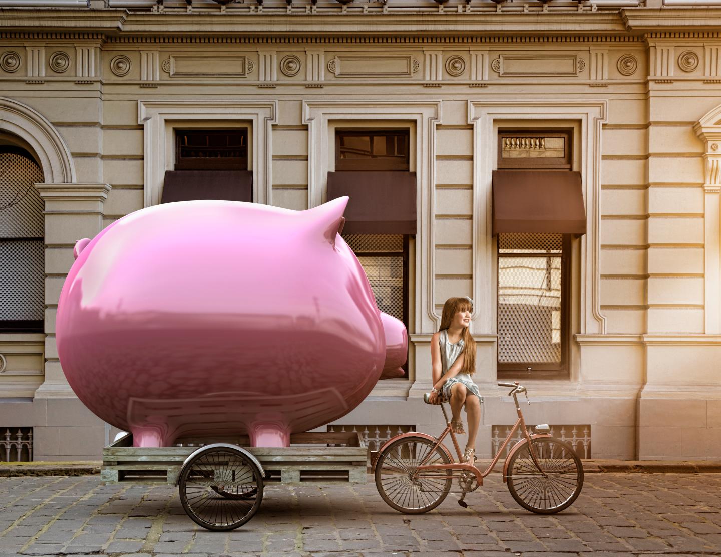 Girl pulling piggy bank on bicycle cart