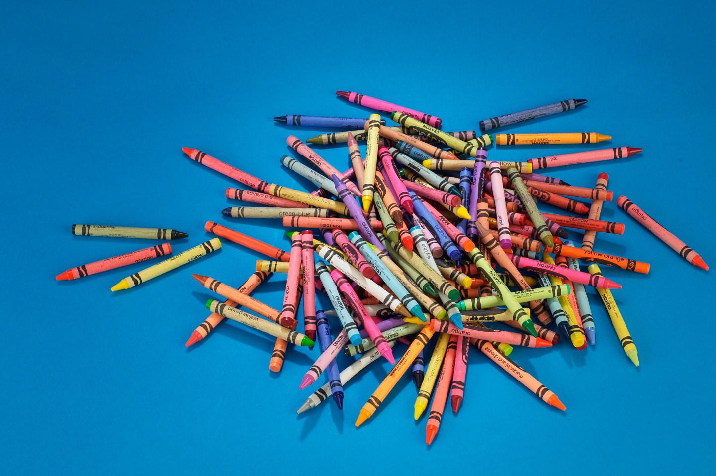 Still life of multicolored crayons in a pile on a blue surface