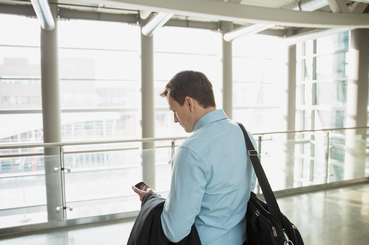 Businessman holding briefcase and texting with smart phone