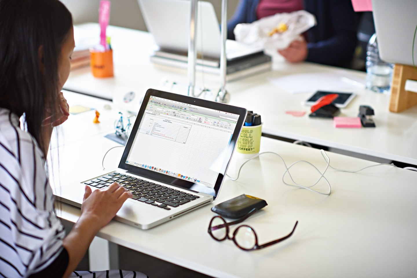 Businesswoman working on a laptop in hot desking start-up office