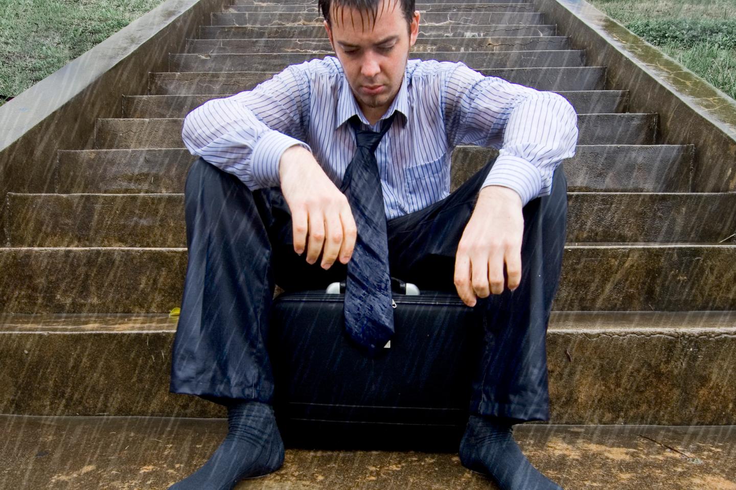 A businessman sits in the pouring rain