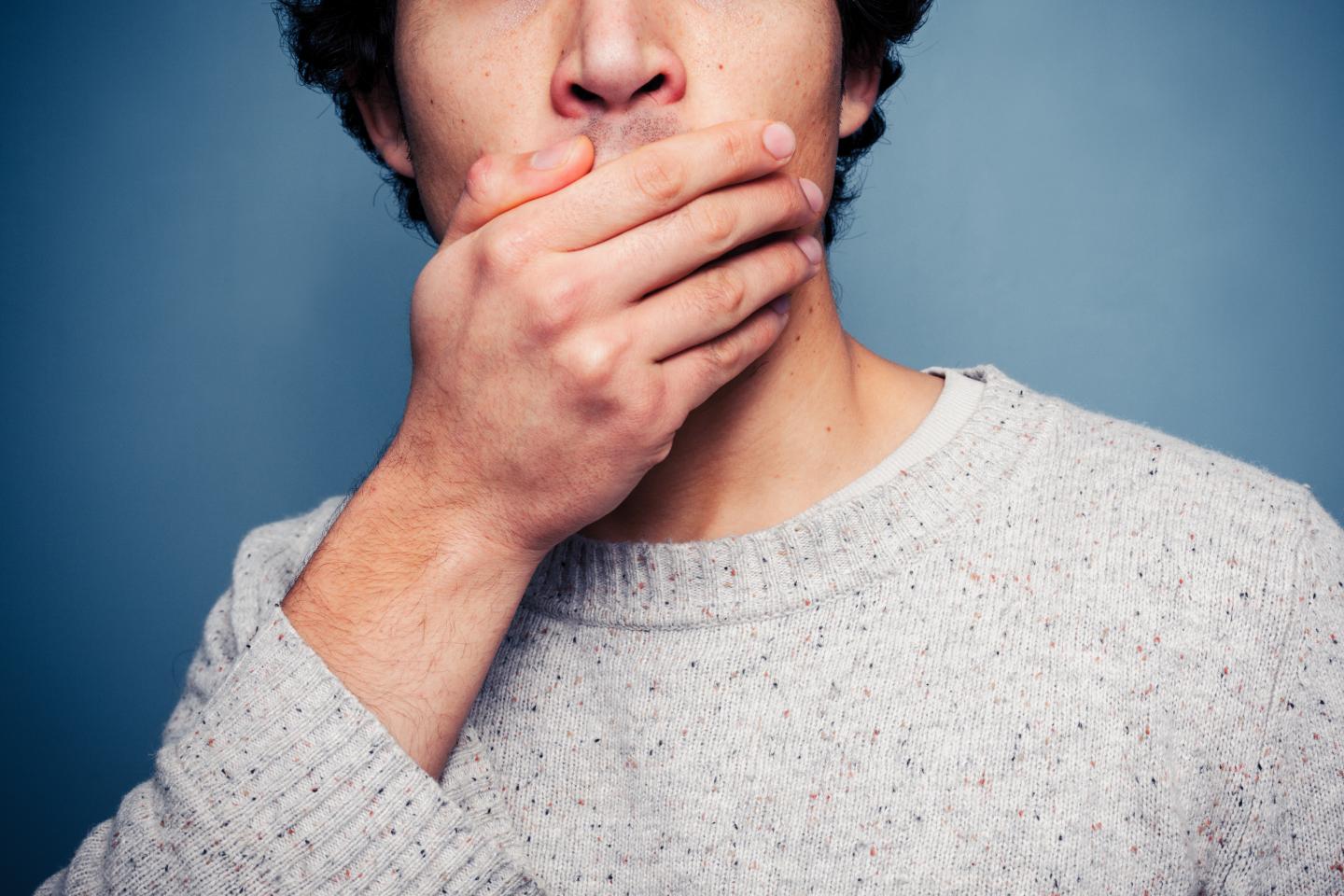 Shocked young man covering his mouth