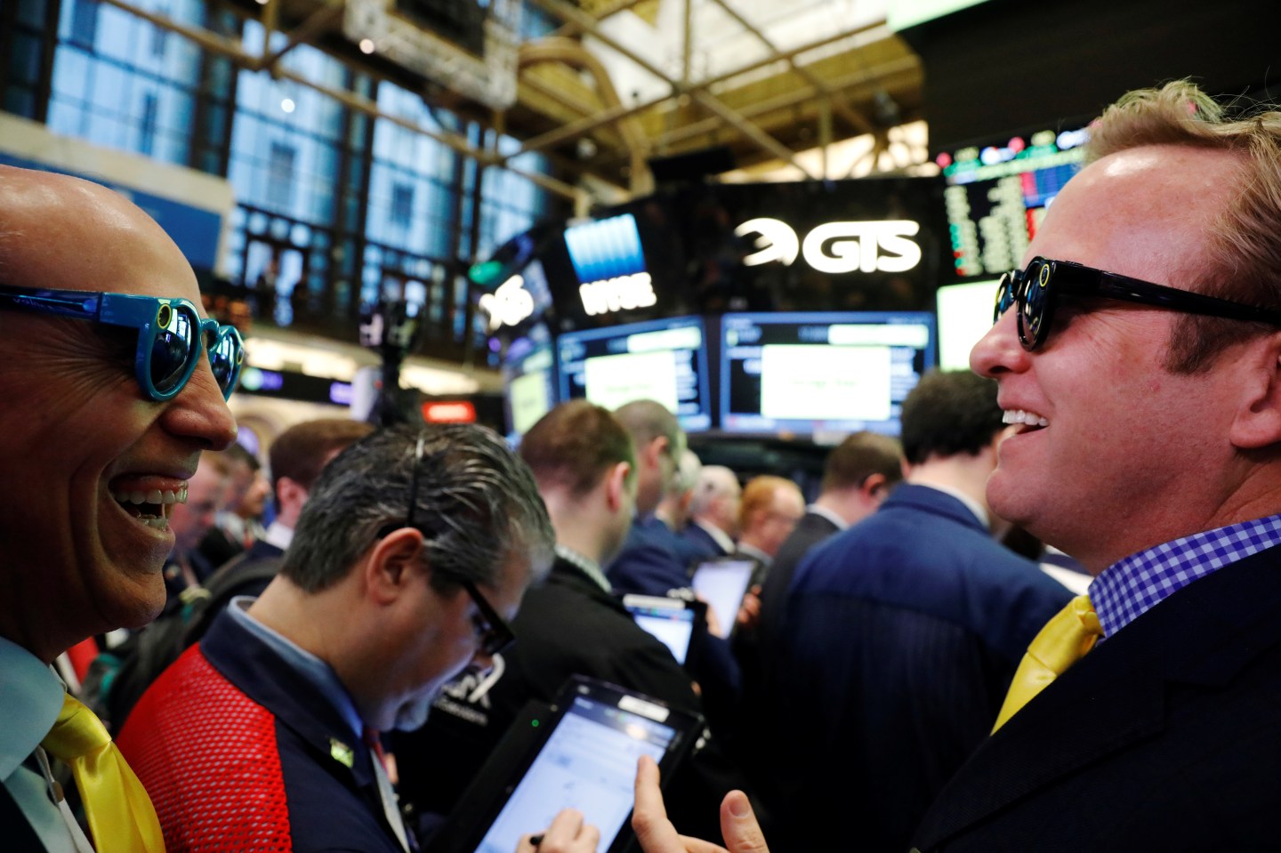 Bankers laugh while wearing Snapchat glasses on the floor of the New York Stock Exchange (NYSE) as they wait for Snap Inc. will post their IPO in New York