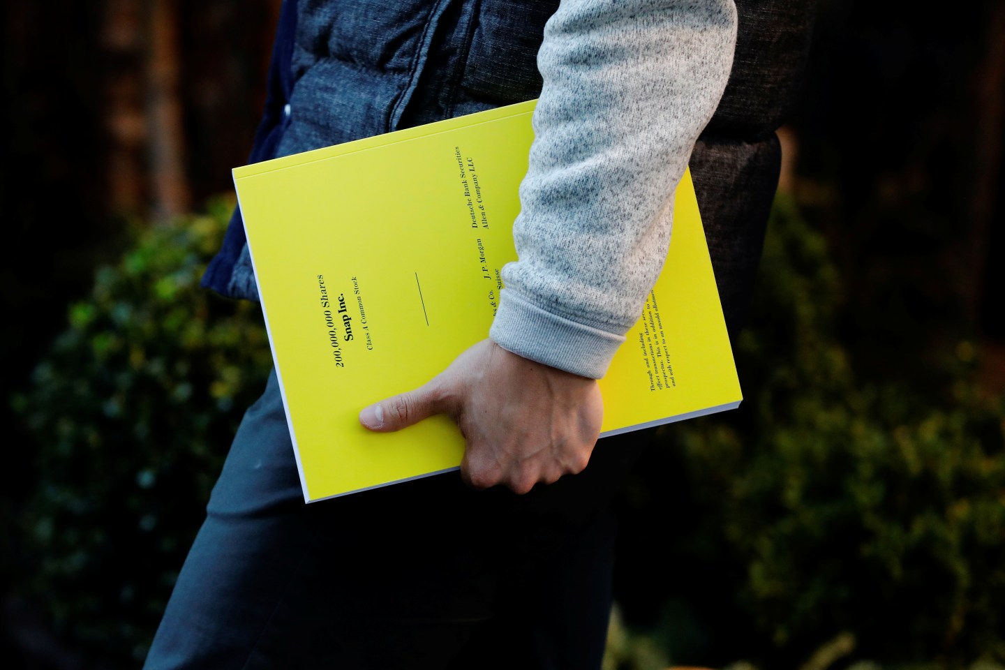 An investor departs the Mandarin Oriental hotel holding a pamphlet of information on investing in the upcoming IPO of Snap Inc. in New York
