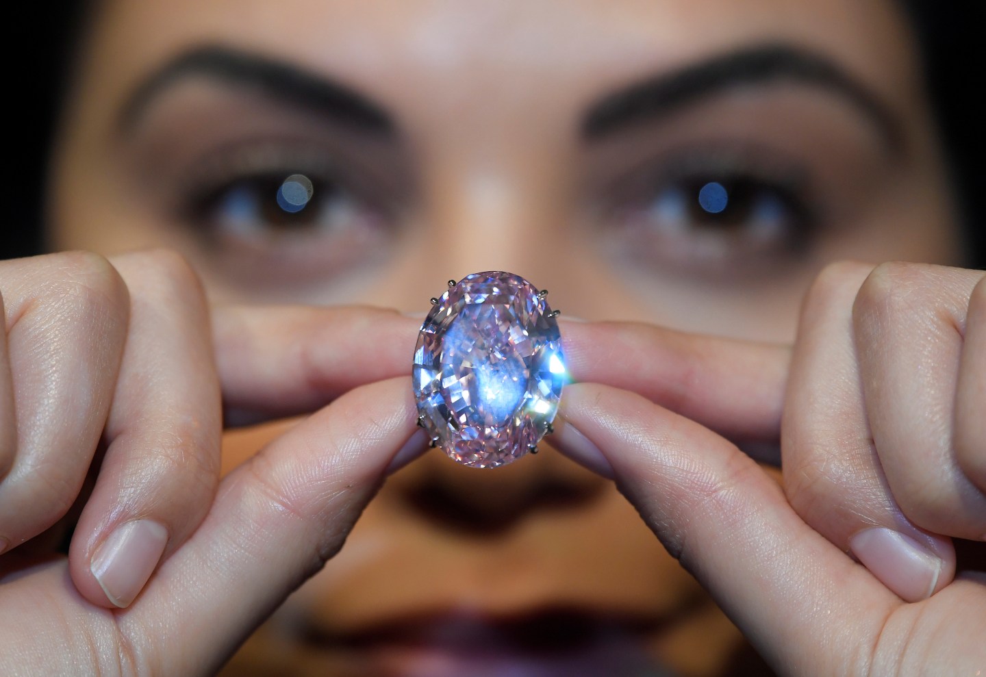 A model poses with a 59.60-carat mixed cut diamond known as "The Pink Star" with a sale estimate of US$ 60 million (GBP £48.4 million), at Sotheby's in London, Britain