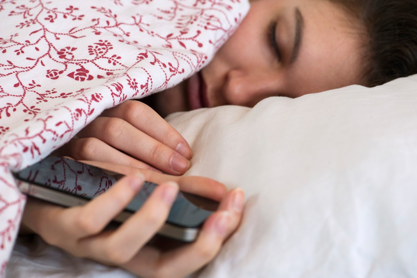 Woman sleeping in bed with smartphone in hand