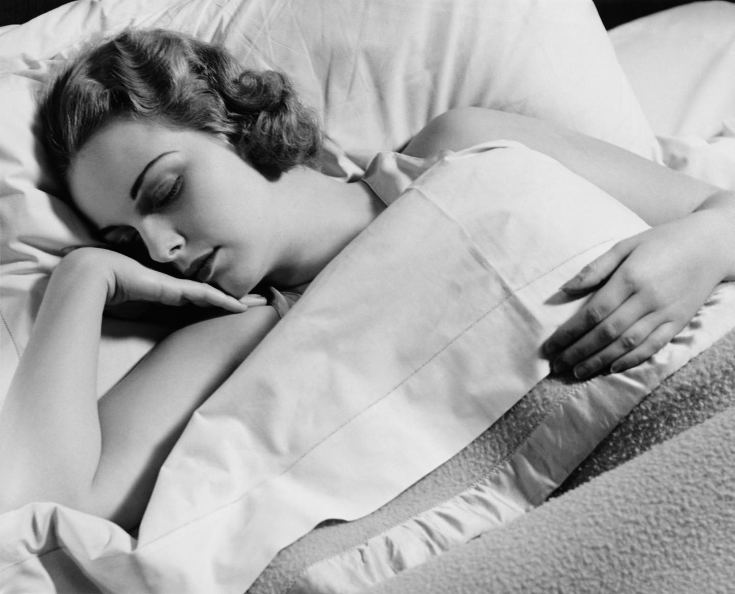 Young woman asleep in bed, (B&amp;W), close-up