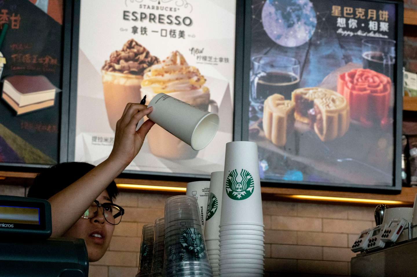 Barista prepares a paper cup in a Starbucks coffee shop.