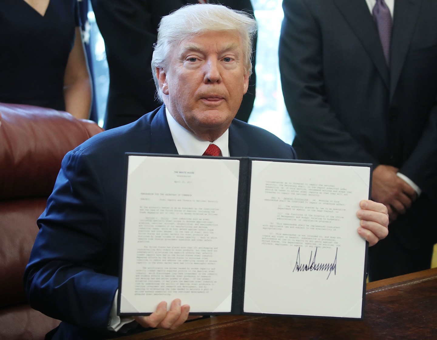 President Trump holds up an Executive Memorandum on the investigation of steel imports, after signing it in the Oval Office at the White House, on April 20.