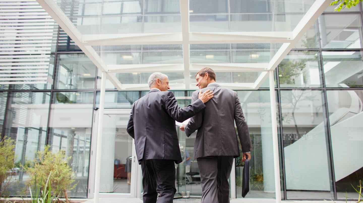 Businessmen walking into office building together
