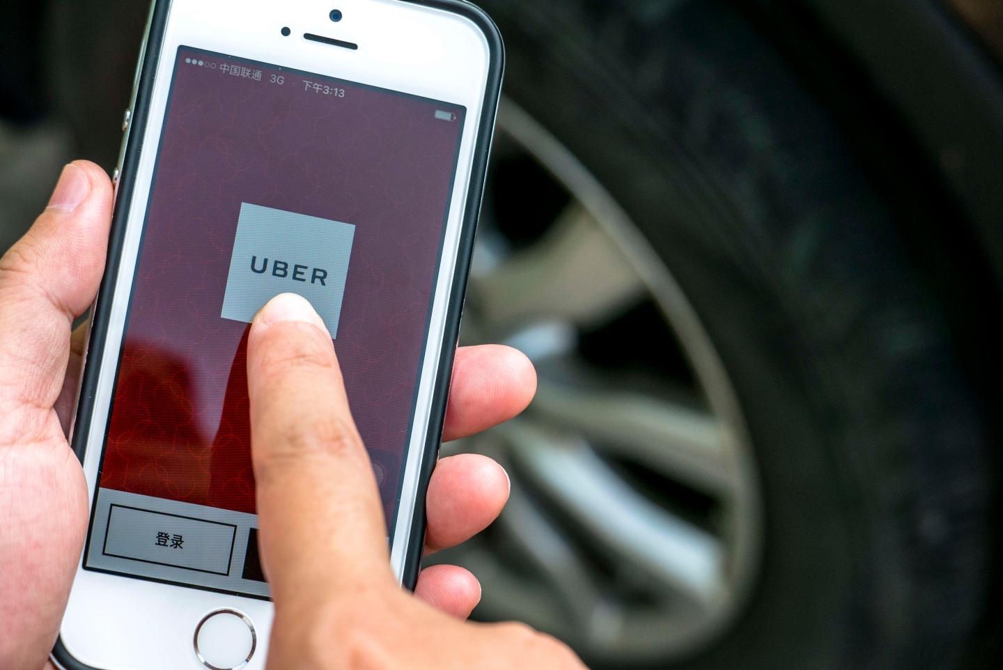 Hand holding a smart phone with Uber App.  Uber is selling
