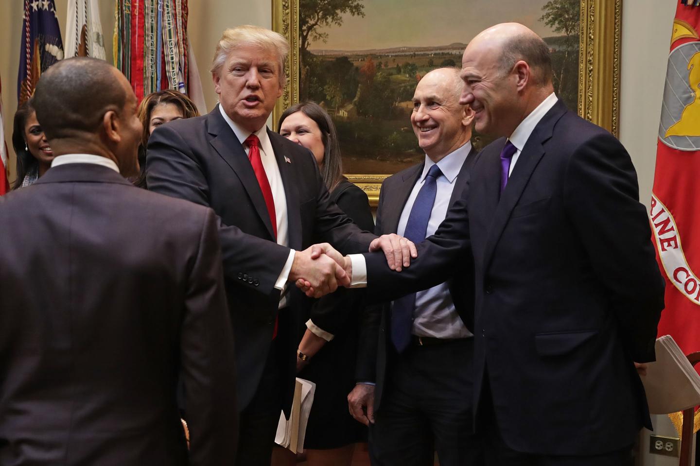 U.S. President Donald Trump (L) calls White House director of strategic initiatives Chris Liddell and White House director of the National Economic Council Gary Cohn (R) ‘geniuses’ at a meeting January 30, 2017 in Washington, DC. The political role for Cohn, a former Goldman Sachs executive, is just one reason investors expected the bank to outperform under the Trump administration.