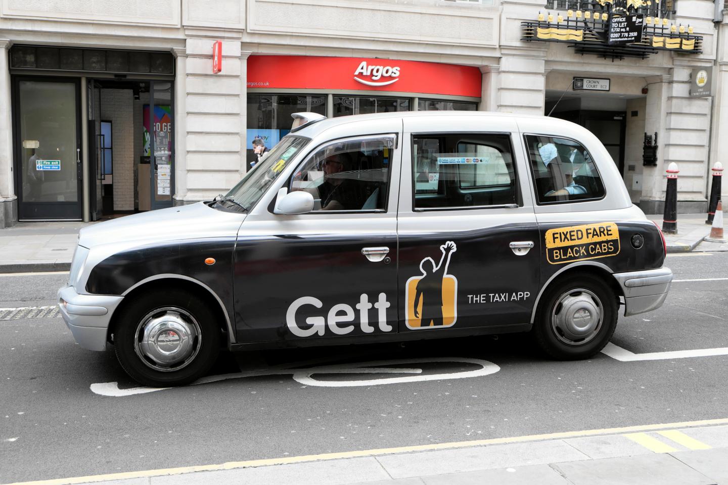 Gett app  "fixed fare"  advert advertisement on black taxi cab in street Cheapside, London UK  KATHY DEWITT