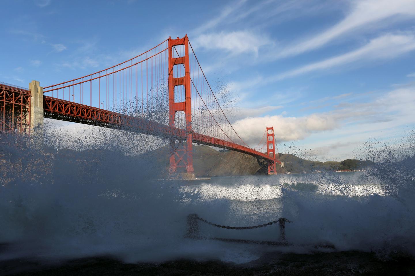 Waves crash against a sea wall in San Francisco Bay beneath the Golden Gate Bridge in San Francisco