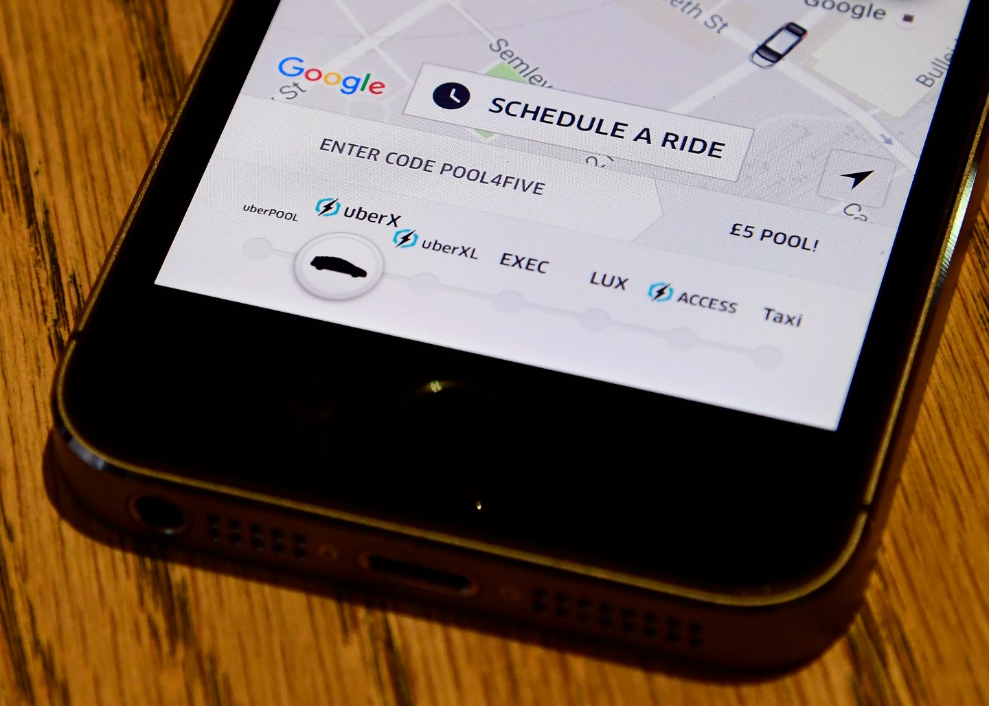 A photo illustration shows the Uber app logo displayed on a mobile telephone, as it is held up for a posed photograph in central London