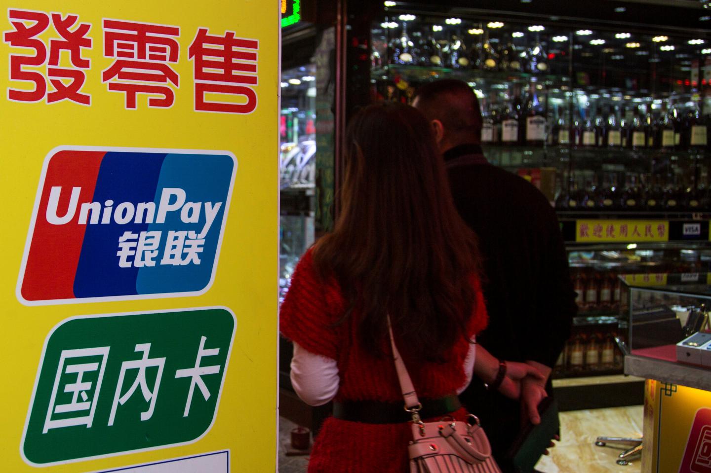 FILE PHOTO - Chinese visitors walk past a sign for China UnionPay outside a pawnshop in Macau
