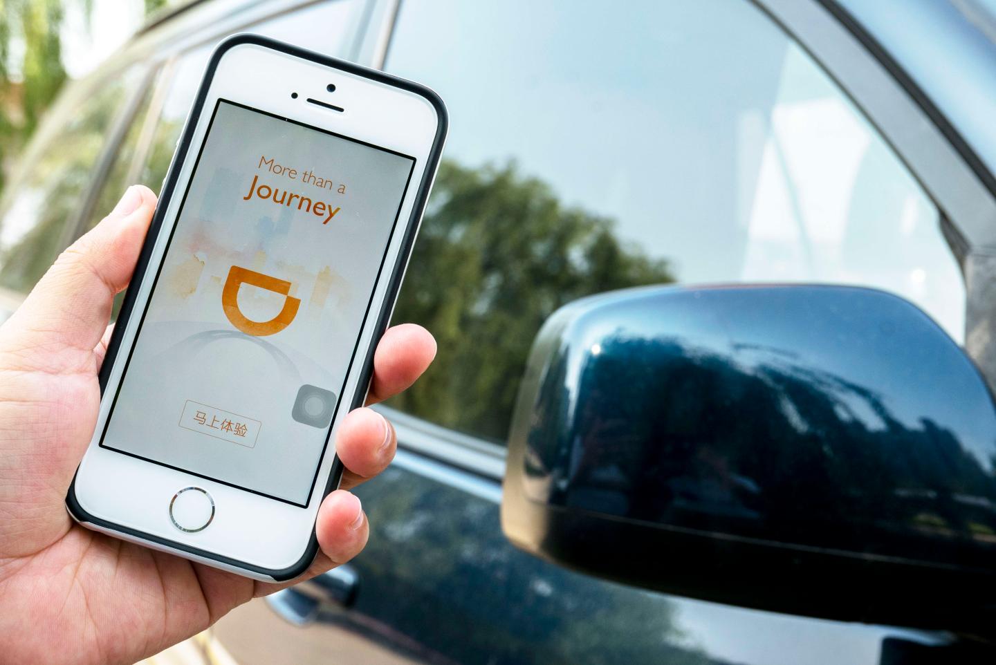 Hand holding a smart phone with an App of Didi Chuxing.
