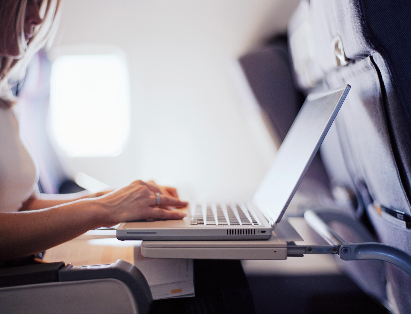 Woman typing on laptop computer in commercial airplane