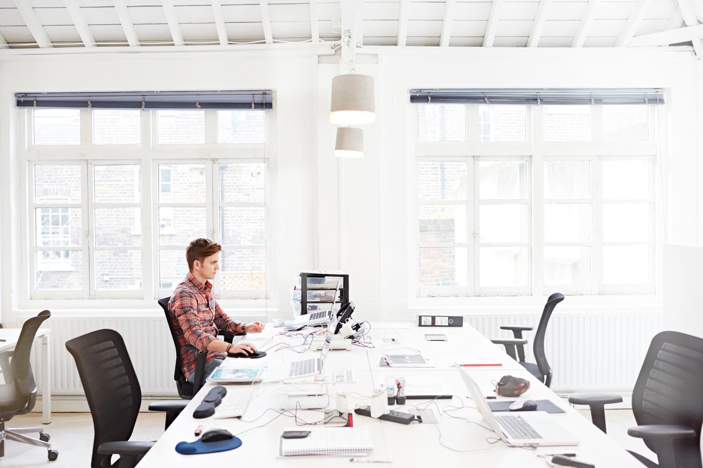 Young employee working in modern open plan office.