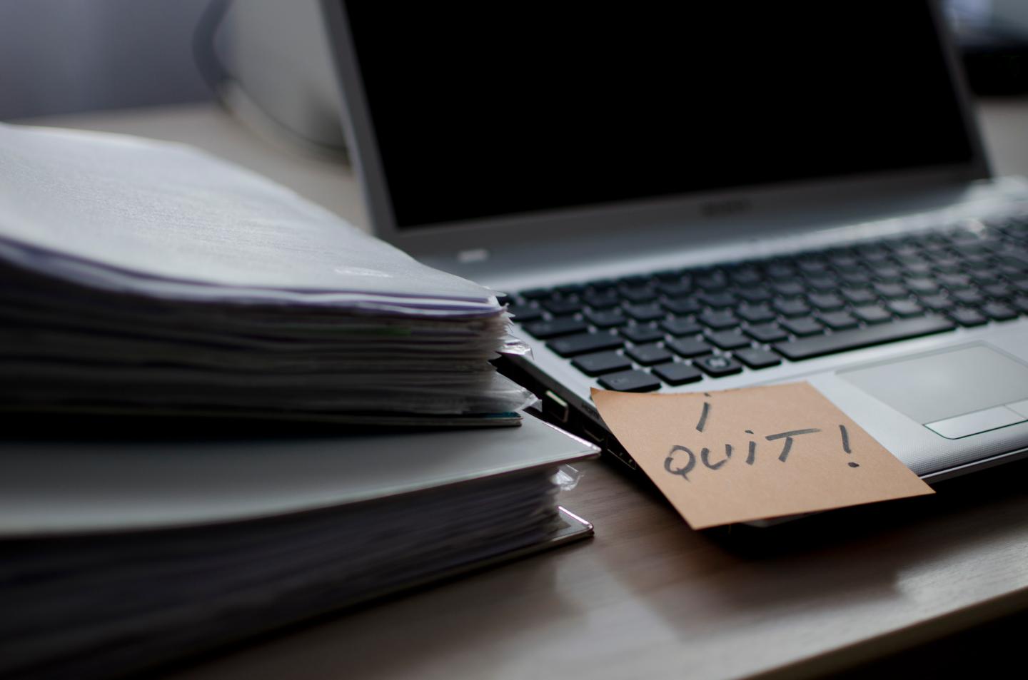 A business desk and laptop with an I quit post it