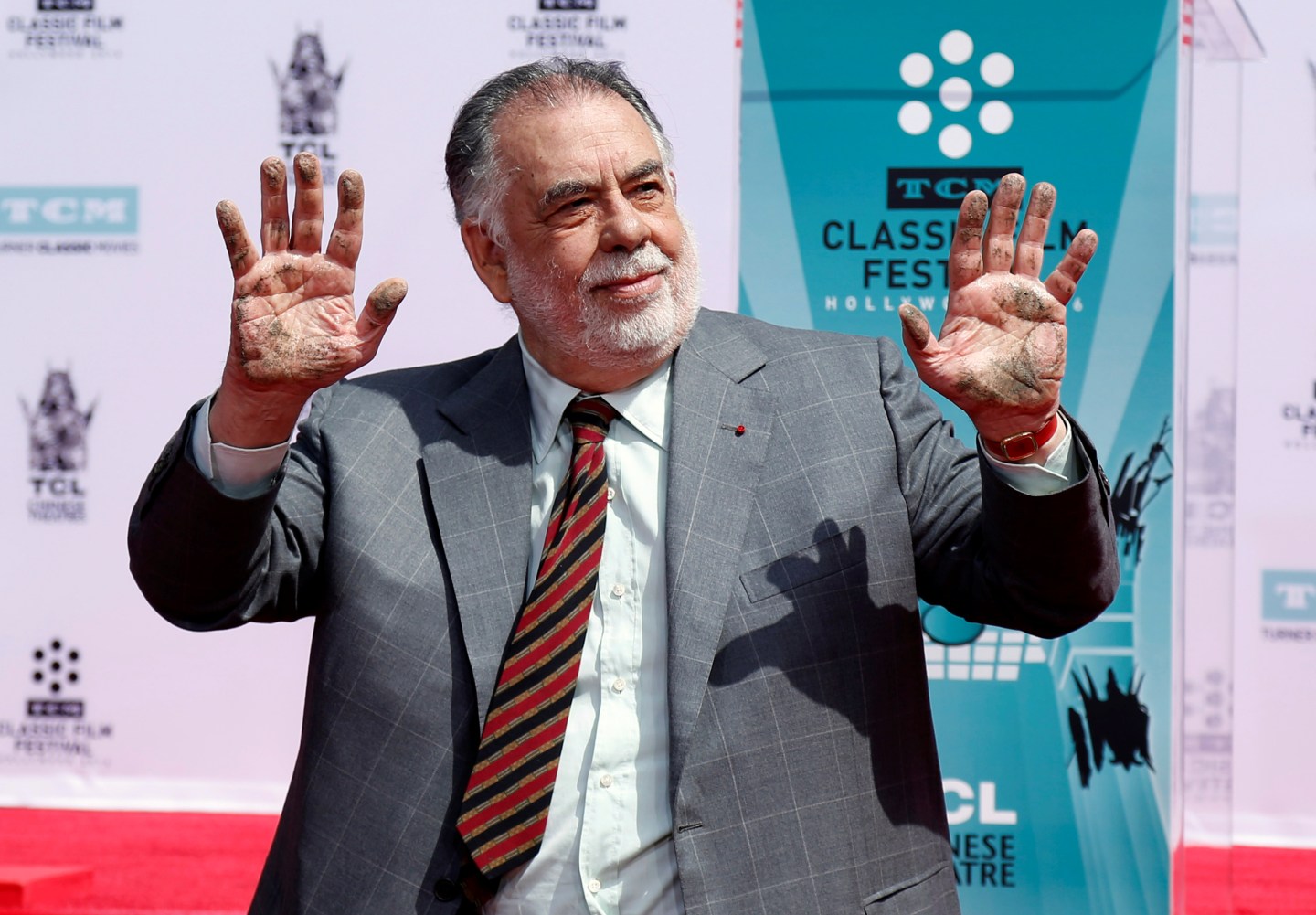 Director Coppola shows his hands after placing his handprints in cement during a ceremony in the forecourt of the TCL Chinese theatre in Hollywood