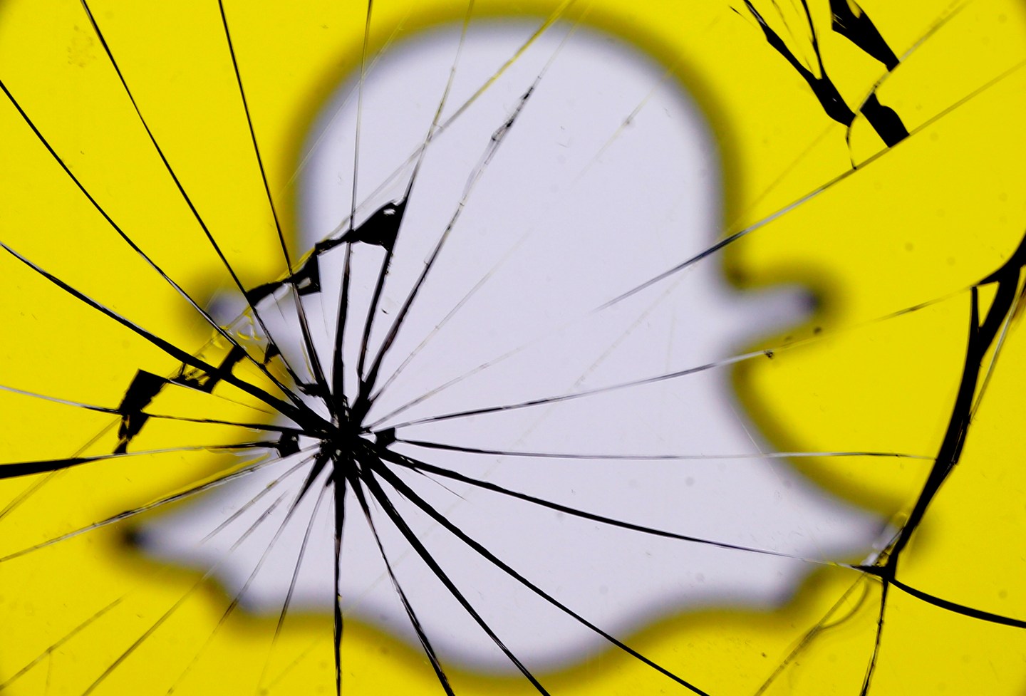 A Snapchat logo is seen through broken glass in this illustration picture