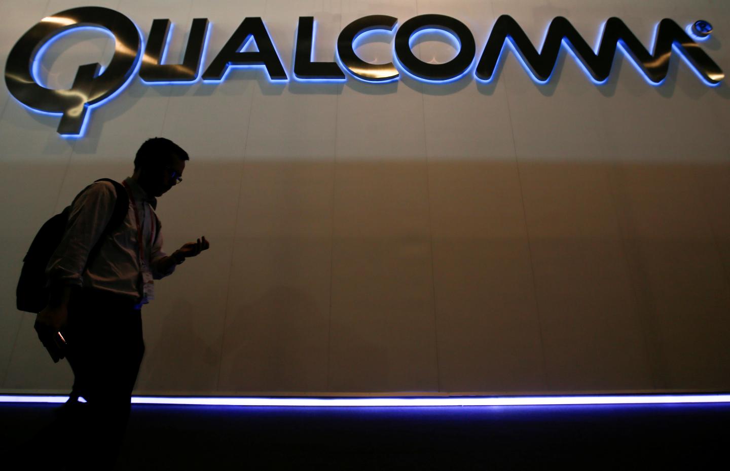 A man walks past Qualcomm stand while attending during the Mobile World Congress in Barcelona